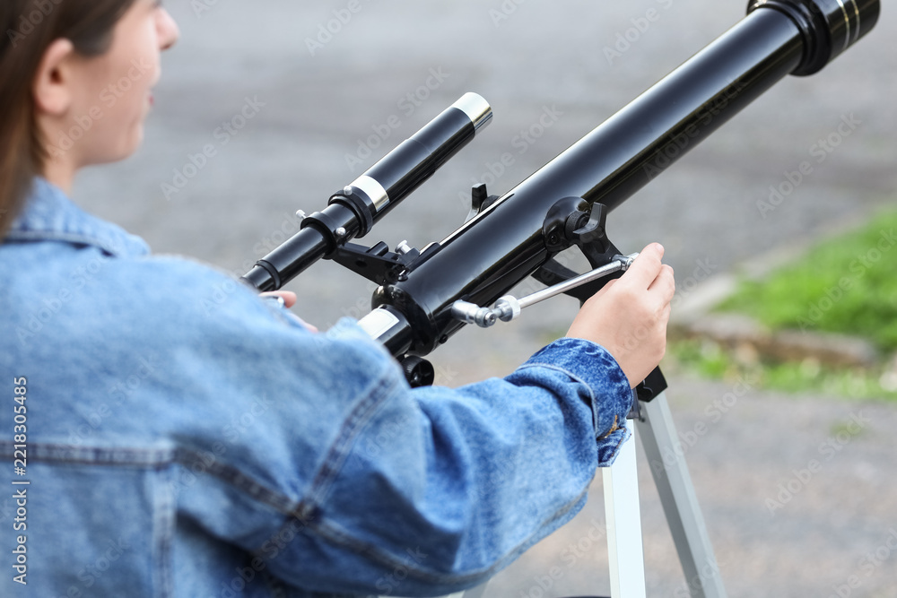 Fototapeta premium Astronomy and science education, young woman using a telescope for stargazing and space exploration in an outdoor setting with curiosity and focus