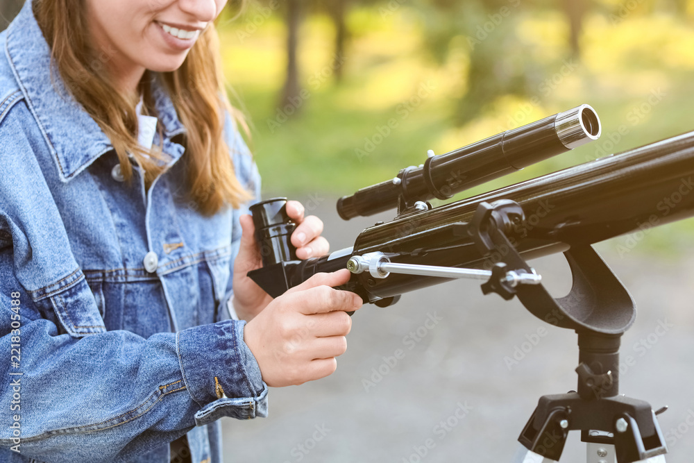 Fototapeta premium Astronomy and science education, young woman using a telescope for stargazing and space exploration in a park during a sunny day