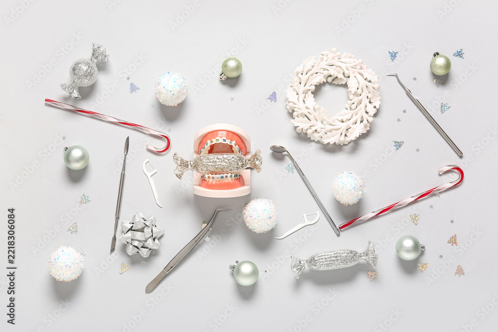 Fototapeta premium Dental health during holidays, orthodontic braces on teeth model with candy and dental tools for oral hygiene awareness in winter festive season