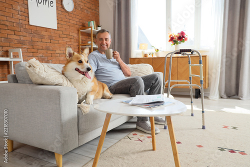 Healthy aging and companionship, senior man relaxing on sofa with corgi dog a...