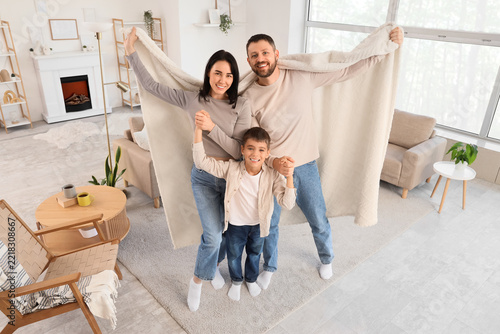 Family bonding and home comfort, happy parents and son holding a soft blanket...