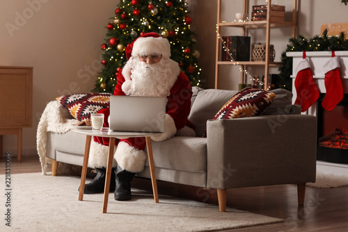 Santa Claus using laptop on sofa at home