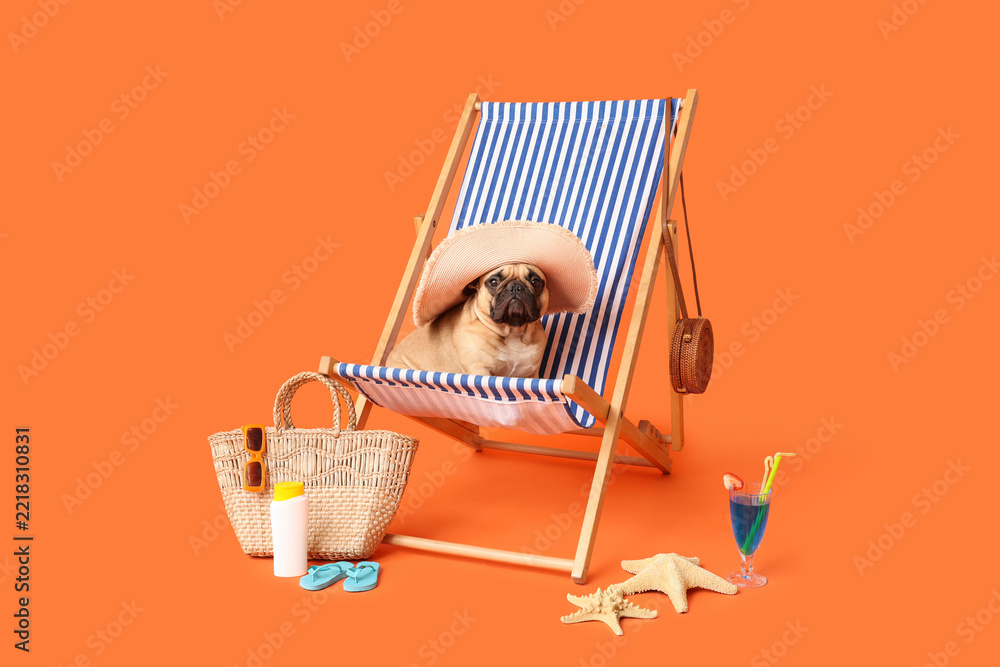 Fototapeta premium Summer vacation and travel concept, cute pug dog wearing sun hat sitting on a beach chair with tropical accessories on a bright orange background