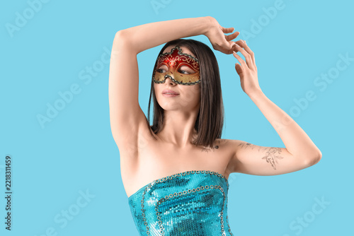 Beautiful young woman in carnival mask on blue background