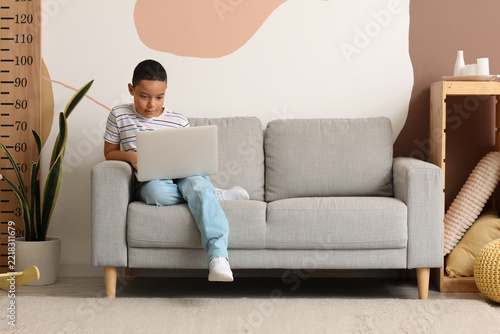 Remote learning and digital childhood, young boy using a laptop for online ed...