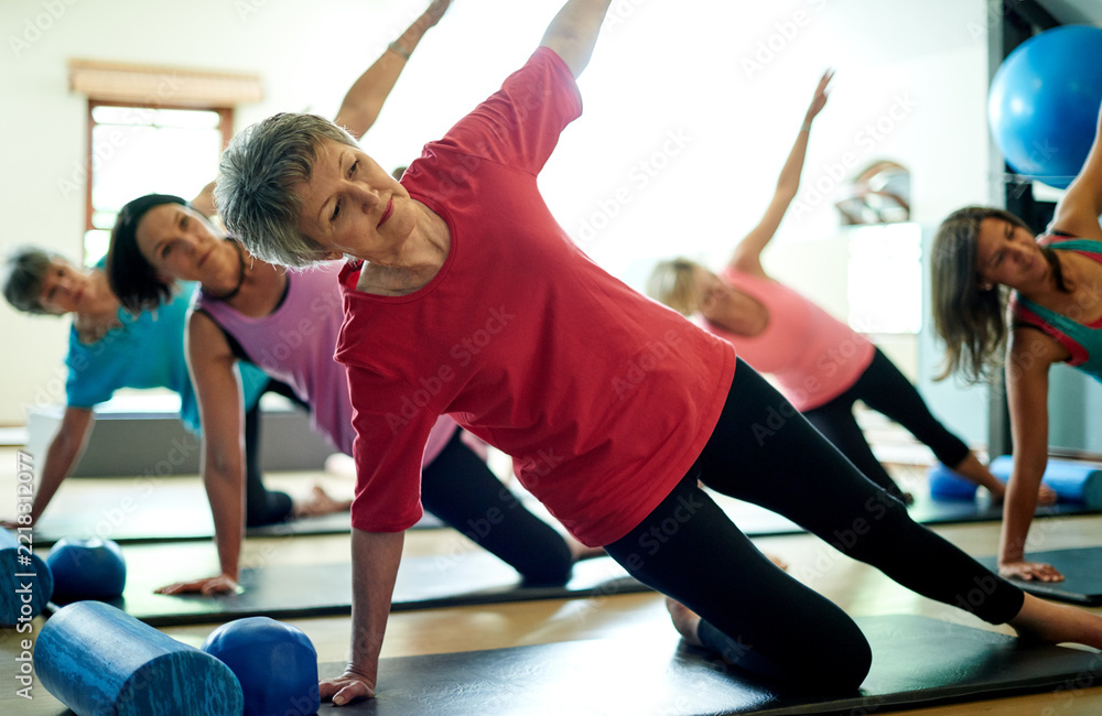 Naklejka premium Active, senior and woman in pilates class for wellness, mobility exercise and healthy body. Side plank, elderly and female person in gym studio for workout, fitness training and physical wellbeing.