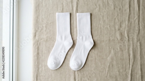 Pair of white crew socks on beige linen fabric