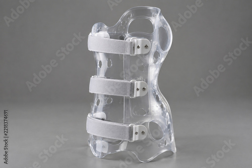 Transparent spinal orthosis on grey background, showcasing its form and clarity.