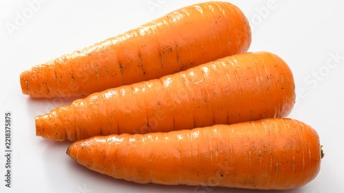 Three fresh vibrant orange carrots arranged on white background, agricultural product photography