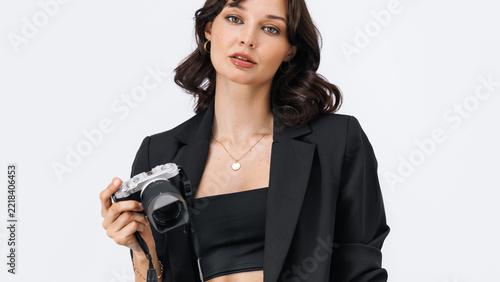 Young Woman Holding Camera in Black Blazer on White Background