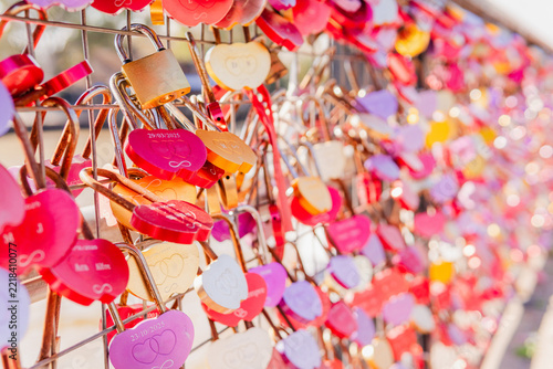Close up of colorful heart shaped love padlocks locked on a metal fence