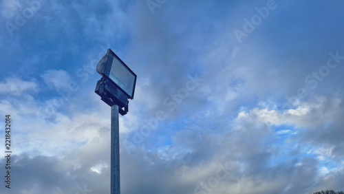Tall Stadium Floodlight Pole Against Cloudy Blue Sky