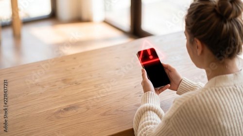 Woman looking at a red warning alert on a smartphone screen 