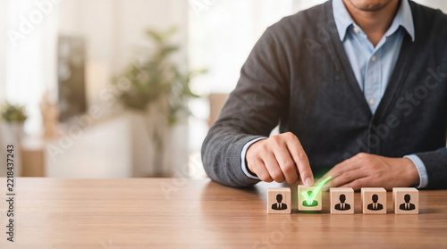 HR manager selecting a candidate wooden block with a green checkmark from a row on a desk