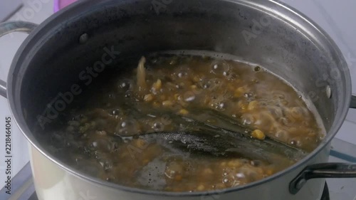 cooking traditional green bean porridge in a stainless steel pot with boiling bubbles