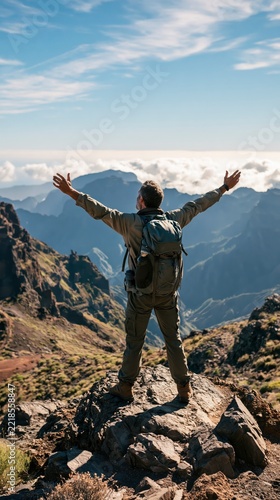 Hiker standing with arms raised on mountain peak, enjoying the panoramic view above the clouds.