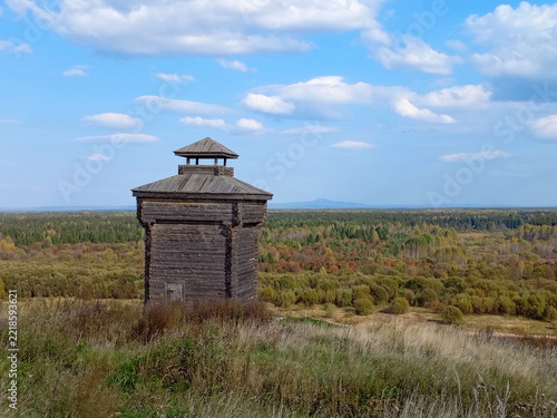 Old wooden watchtower in the forest on a background of blue sky in Cherdyn, Russia