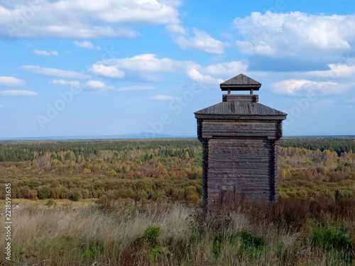 Old wooden watchtower in the forest on a background of blue sky in Cherdyn, Russia