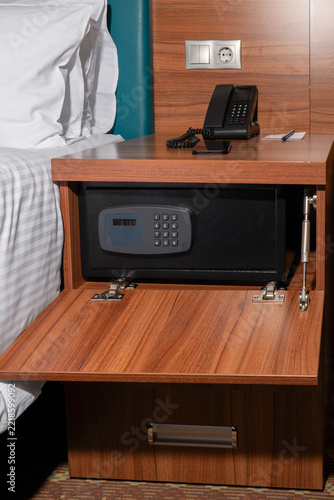 Electronic safe built into a wooden nightstand in a modern hotel bedroom