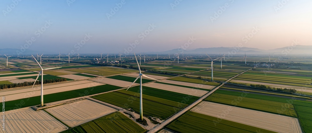 Naklejka premium Aerial view of wind turbines scattered across cultivated fields in rural countryside