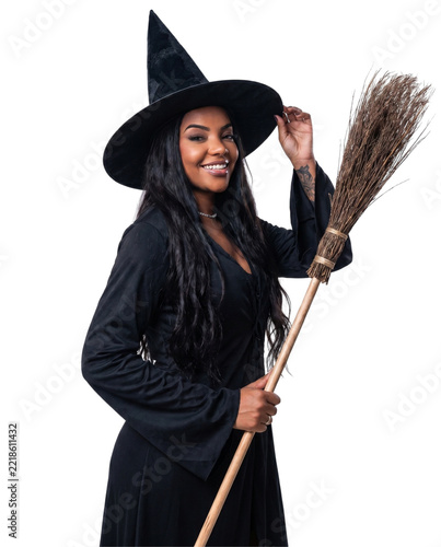 Portrait of a smiling young woman in a Halloween witch costume holding a broomstick