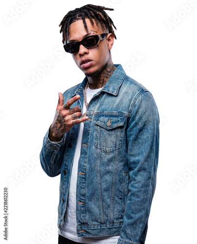 Portrait of a confident young Black man with dreadlocks, sunglasses, and tattoos wearing a denim jacket