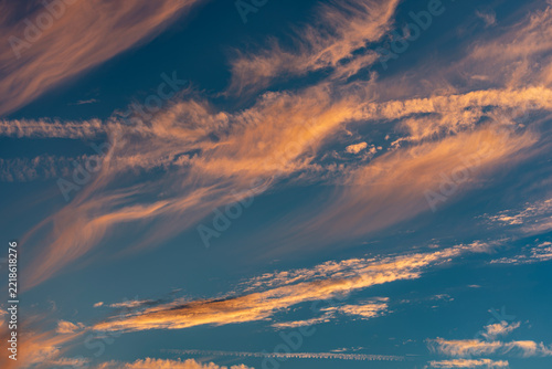 Stimmungsvoller Abend-oder Morgenhimmel mit blauem Hintergrund und von der tiefstehenden Sonnen orange angestrahlten Cirruswolken