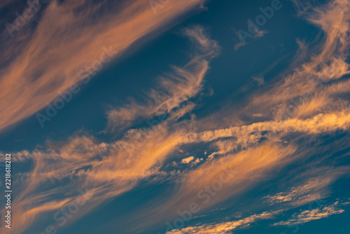 Stimmungsvoller Abend-oder Morgenhimmel mit blauem Hintergrund und von der tiefstehenden Sonnen orange angestrahlten Cirruswolken