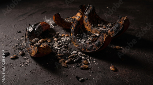 Charred Pumpkin Pieces with Seeds on Dark Texture