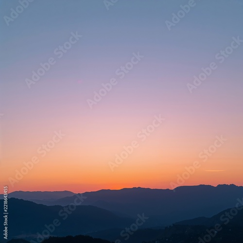 Serene mountain range at golden hour with soft pastel sky