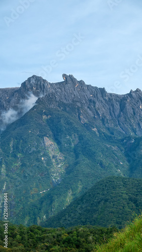 Many peaks Mount Kinabalu is highest tropical mountain in Borneo, jagged mountain peaks. Clouds hide in gorges. Geological rise of adolescent mountains continues. Landscape of once Mysterious Island