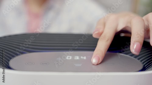 Close-up, hand of woman turns on PM 2.5 air purifier or adjust at home