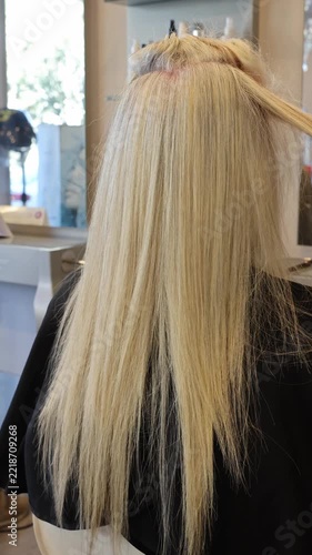 Hairdresser blow-drying long blonde hair with a round brush in a salon