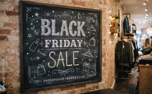 Black Friday Sale Chalkboard Sign on Brick Wall in Clothing Boutique Retail Store Shopping Promotion Concept