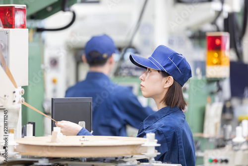 工場内で製造機械を操作しながら作業を行う女性作業員の横顔