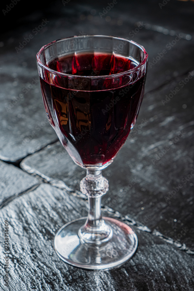 Fototapeta premium Elegant red wine served in a detailed crystal glass on a dark stone table