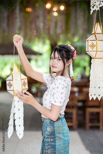 Beautiful Asian woman in traditional Thai dress holding paper lantern during Lanna Loy Krathong festival.