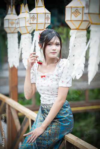 Beautiful Asian woman in traditional Thai dress holding paper lantern during Lanna Loy Krathong festival.