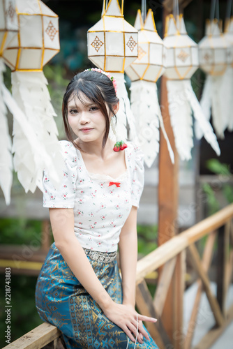 Beautiful Asian woman in traditional Thai dress holding paper lantern during Lanna Loy Krathong festival.