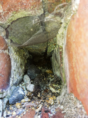 Abandoned Brick Wall Cavity with Cobwebs and Debris
