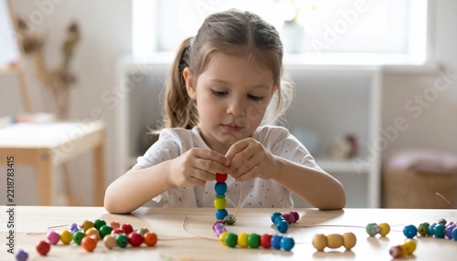 Child Practicing Fine Motor Skills with Colorful Beads