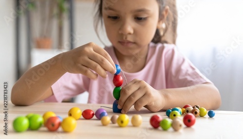 Child Practicing Fine Motor Skills with Colorful Beads