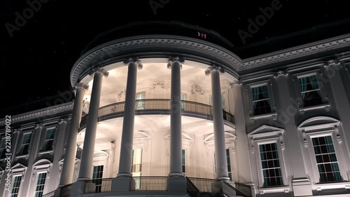 3D animation of the White House facade at night, featuring illuminated classical architecture, columns, windows and the American flag against a dark starry sky.