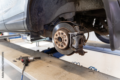Pneumatic impact wrench on a lift platform with air hose, close-up of tire change tools in an auto repair garage