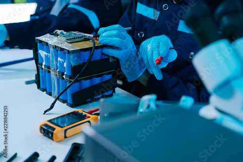 Engineer testing a battery pack with a multimeter in a high-tech lab, exploring BMS, renewable energy storage, electrical testing, clean power, and battery innovation.