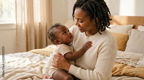 Black mother and African American baby sharing a tender moment, looking at each other in a cozy home bedroom, ideal for parenting blogs, family wellness websites, and maternal health awareness.