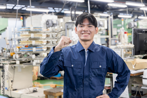 製造工場で笑顔でガッツポーズをする若い外国人労働者・日本の製造業で活躍する外国人材