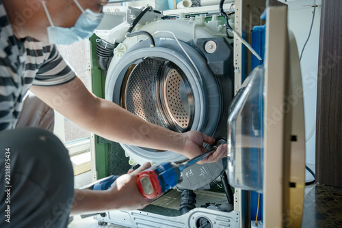 Obraz na plátně Technician Repairing A Front Loading Washing Machine With Power Tool