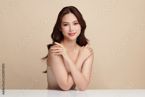 A beautiful young Asian woman with clean, fresh skin against a beige background. Skincare, facial treatment, cosmetology, beauty, and spa. An elegant portrait of an Asian woman.