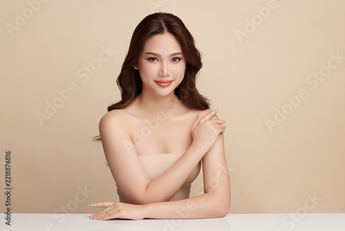 A beautiful young Asian woman with clean, fresh skin against a beige background. Skincare, facial treatment, cosmetology, beauty, and spa. An elegant portrait of an Asian woman.